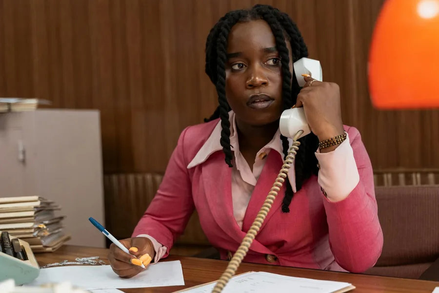woman in a pink blazer talking on a telephone