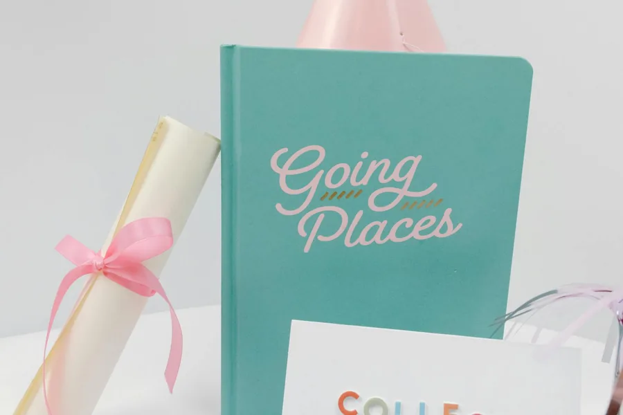 turquoise book and white rolled paper with pink ribbon