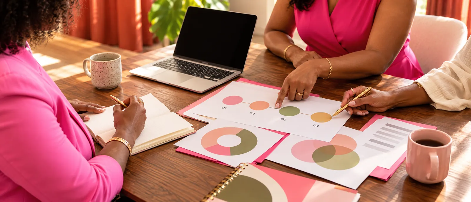 Three women working together at a sunlit table over a printed planning roadmap